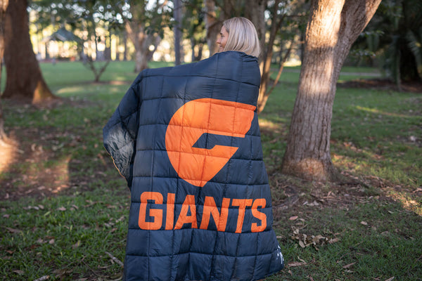 Navy and orange Giants puffy blanket with team logo, worn over shoulders outdoors