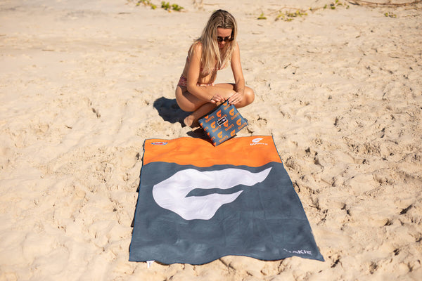 GWS Giants navy and orange beach towel with white logo, sand-free material, displayed on sand
