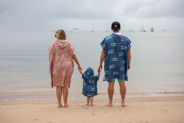 Kids hooded towel in navy with white stripe pattern, worn by child at beach