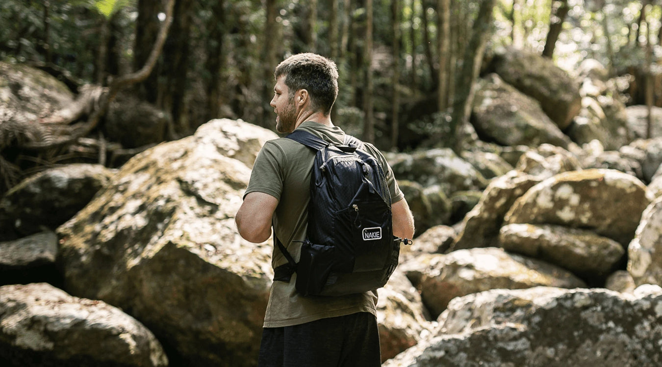 Man hiking in forest with sustainable Nakie backpack made from recycled plastic bottles, ideal eco-friendly hiking gear
