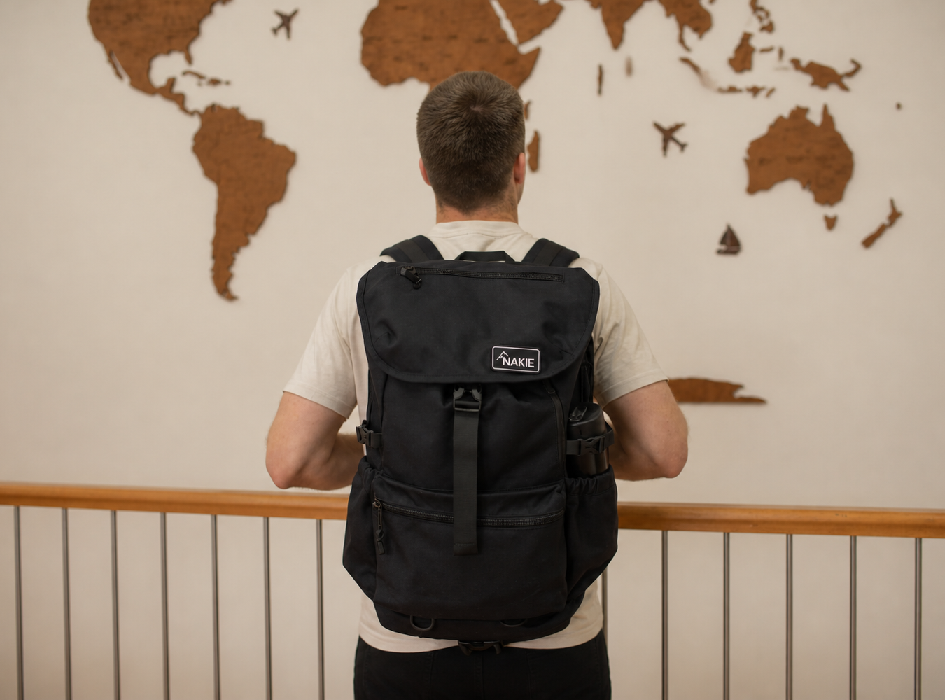 Black recycled travel backpack with flap closure, side pockets, and branded label, worn on back view.