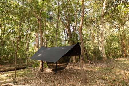 A Nakie hammock ultralight no knot tarp fully set up at a campsite, demonstrating effortless outdoor comfort with eco-friendly gear.