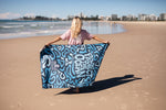 Recycled sand-free beach towel with blue abstract wave pattern, displayed on sandy beach by ocean. preview #7