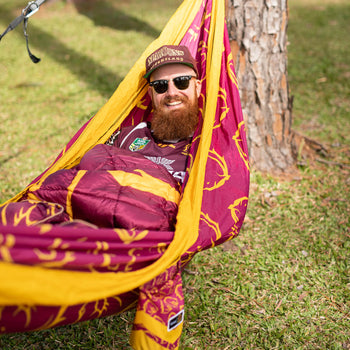 Man relaxing in a Nakie NRL Broncos Hammock outdoors