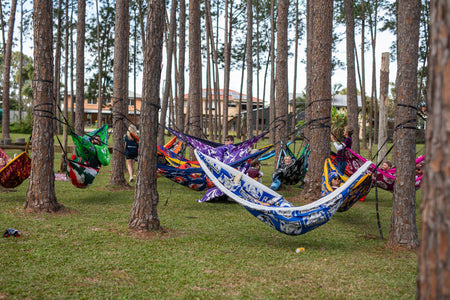 Colorful Nakie NRK hammocks hanging between trees in a park setting with lots of happy people.