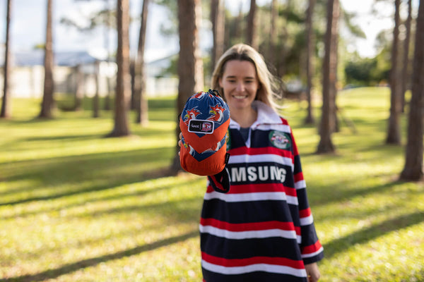 Red and navy Roosters recycled hammock with dragon print design, displayed by person holding it open in park setting