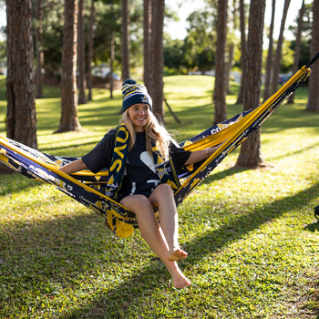 Person sitting in a Nakie NRL Cowboys hammock with trees in the background
