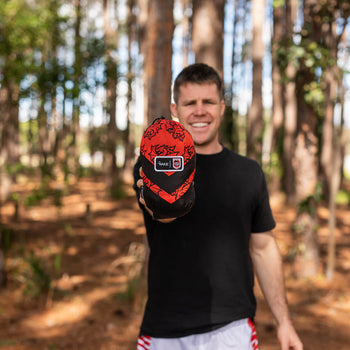 Man holding a NRL Dragons Hammock packed away into its stuff-sack for easy storage