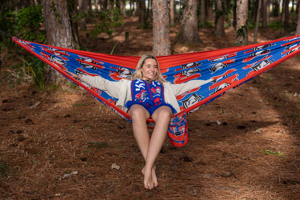 Red and blue Knights NRL patterned recycled hammock with included straps, displayed in forest setting