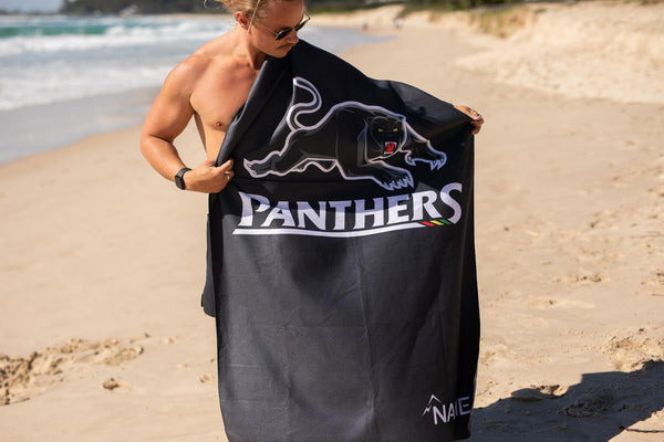 Black Panthers NRL beach towel with panther graphic and white text, displayed on beach