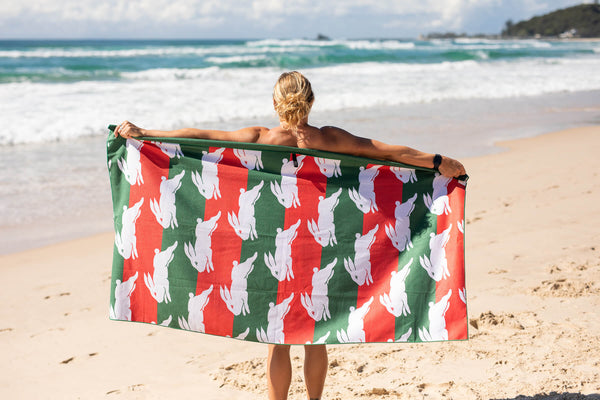 Recycled sand-free beach towel with green, red, and white striped rabbit pattern, displayed on beach
