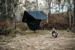 Woman setting up a Nakie ultralight no knot tarp at a campsite, demonstrating easy assembly and portability for outdoor adventures. preview #5