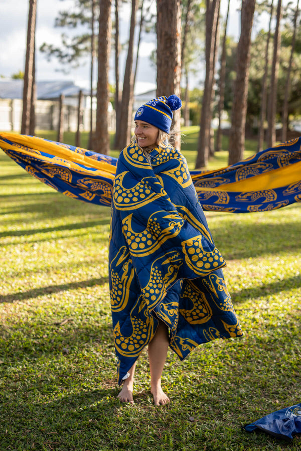 Blue and gold Eels NRL patterned puffy blanket wrapped around child outdoors, matching beanie visible