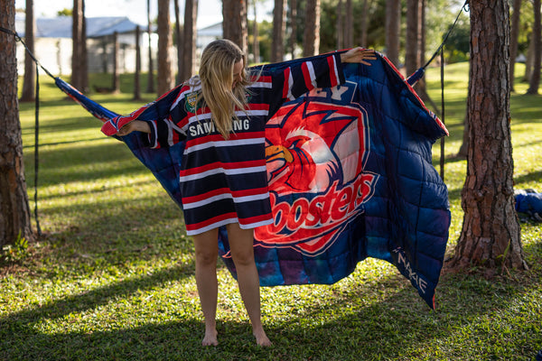 Roosters NRL red and navy striped down puffy blanket with rooster logo, displayed outdoors.