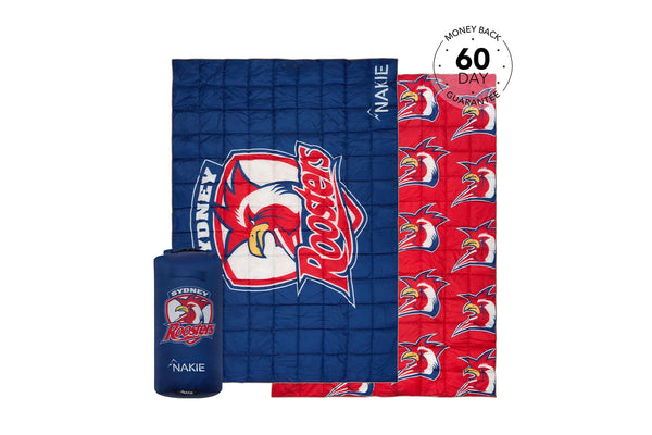 Reversible Sydney Roosters NRL puffy blanket, navy and red with team logo and rooster pattern, shown with stuff sack.