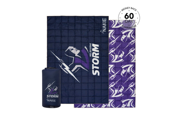 Navy and purple quilted puffy blanket with Storm logo and geometric pattern, shown folded with matching stuff sack