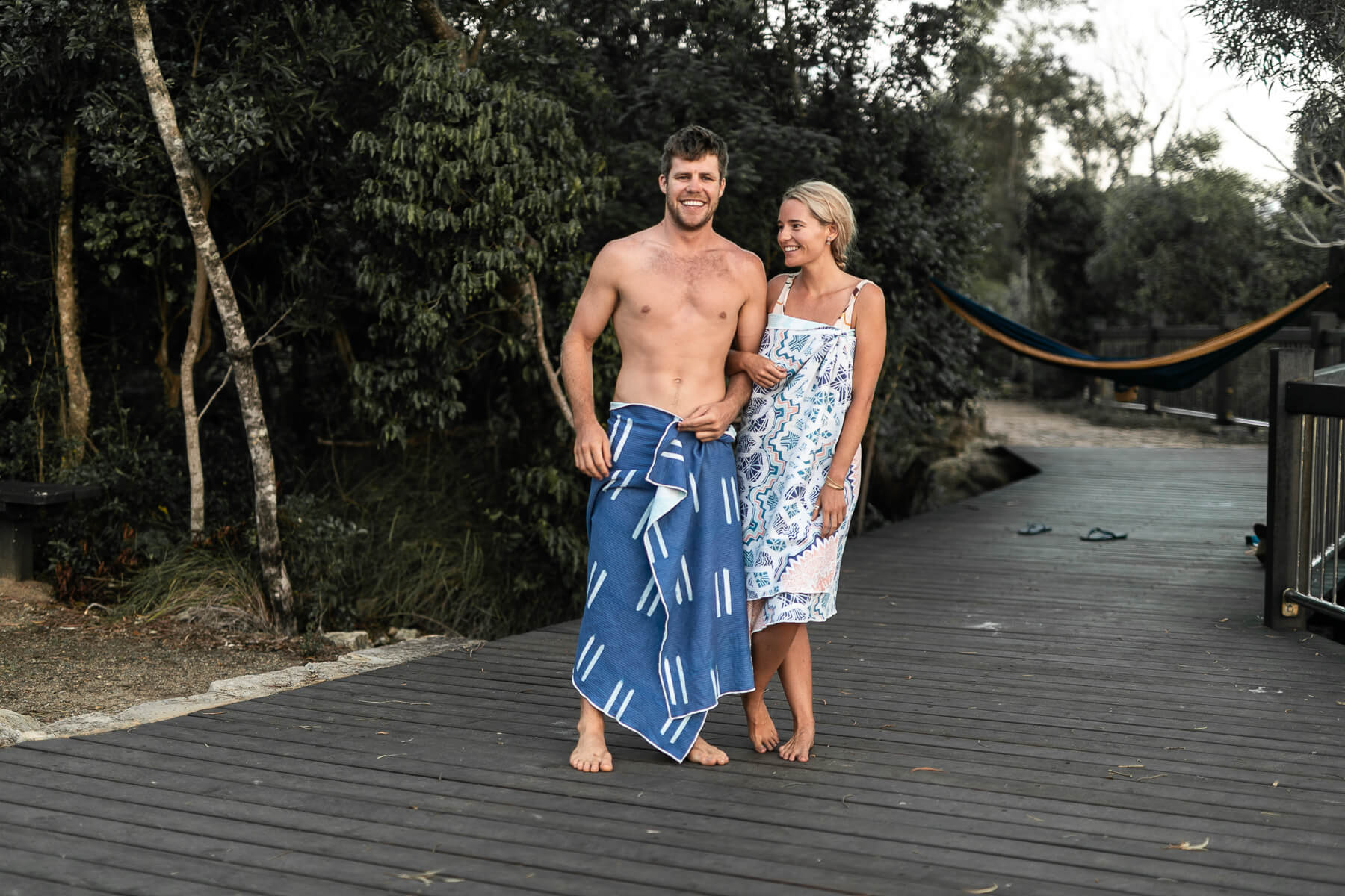 Image of a couple wearing Nakie's couple combo recycled sand-free beach towels, enjoying a sustainable and comfortable beach outing together.